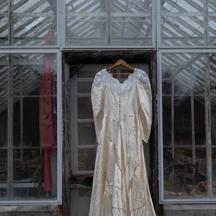 Diptych: Left - wedding dress on a hanger suspended in the doorway of a metal framed glass building; Right: Dress on a hanger, 'lounges' in front of three lobster pots.