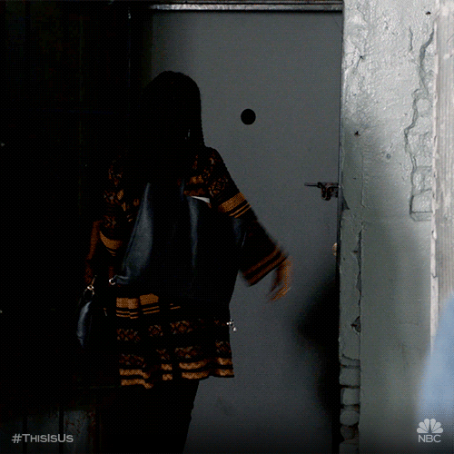 Beth della serie tv This is Us è di spalle e cammina verso una porta. Mostra le due dita in segno di vittoria mentre lascia la stanza.