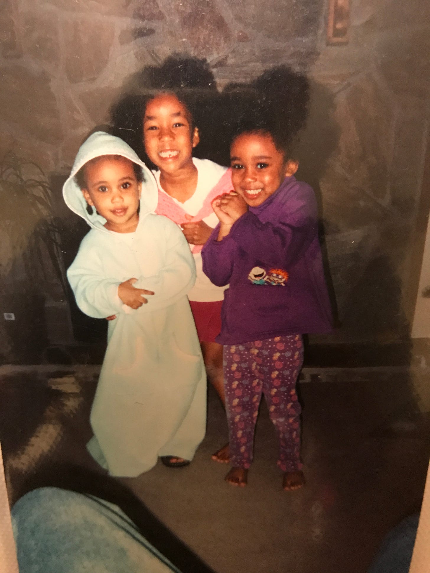 Kiana's 3 little sisters looking bedraggled and in PJs in their living room many years ago.