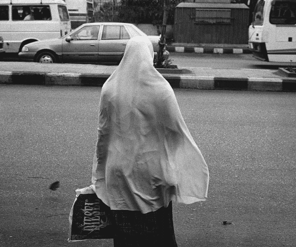 Woman in veil looks onto a busy street