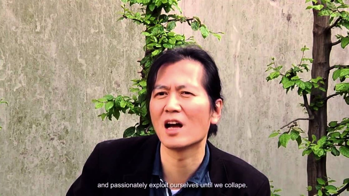 frame de uma entrevista do byung-chul han. ele é um cara coreano e cabelo longo, aqui preso num rabo de cavalo e só com uma madeixa de franja pro lado. ele tá franzindo de boca aberta, no meio de uma fala. na legenda: and passionately exploit ourselves until we collape. frame de uma entrevista do byung-chul han. ele é um cara coreano e cabelo longo, aqui preso num rabo de cavalo e só com uma madeixa de franja pro lado. ele tá franzindo de boca aberta, no meio de uma fala. na legenda: and passionately exploit ourselves until we collape.