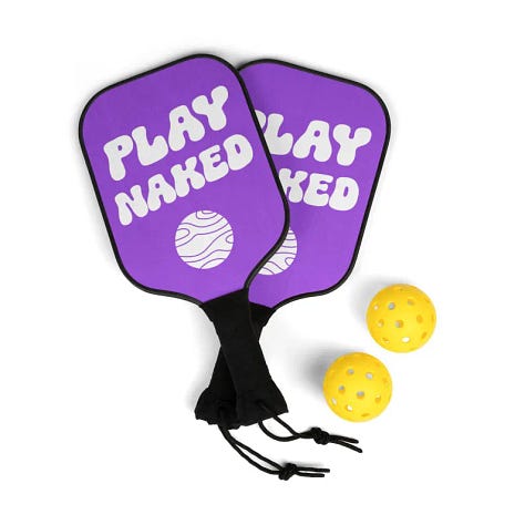 A six-image grid of Planet Nude Etsy products: top left, a humorous beach greeting card showing two giant dinosaurs towering over nude sunbathers; top middle, an amber glass “Live Naked Die Happy” candle; top right, a bright green “Clothing Optional Beyond This Point” T-shirt; bottom left, a purple “Play Naked” pickleball set with two paddles and two yellow balls; bottom middle, a coir doormat reading “Clothing Optional Beyond This Point”; bottom right, a retro-style circular patch showing two nude human figures under stars with the caption “Made From Starstuff.”