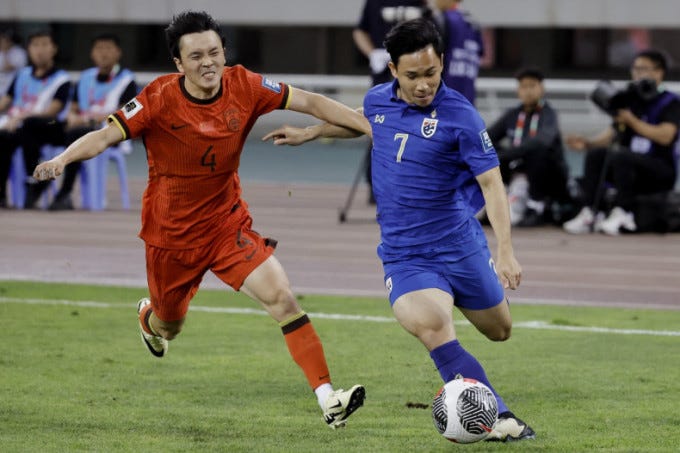 Zhen’ao Wang (L) of China pursues Thailand’s Supachok Sarachat in a 1-1 draw at the World Cup qualifiers at the Shenyang Olympic Sports Center Stadium, June 6, 2024. Photo by Reuters
