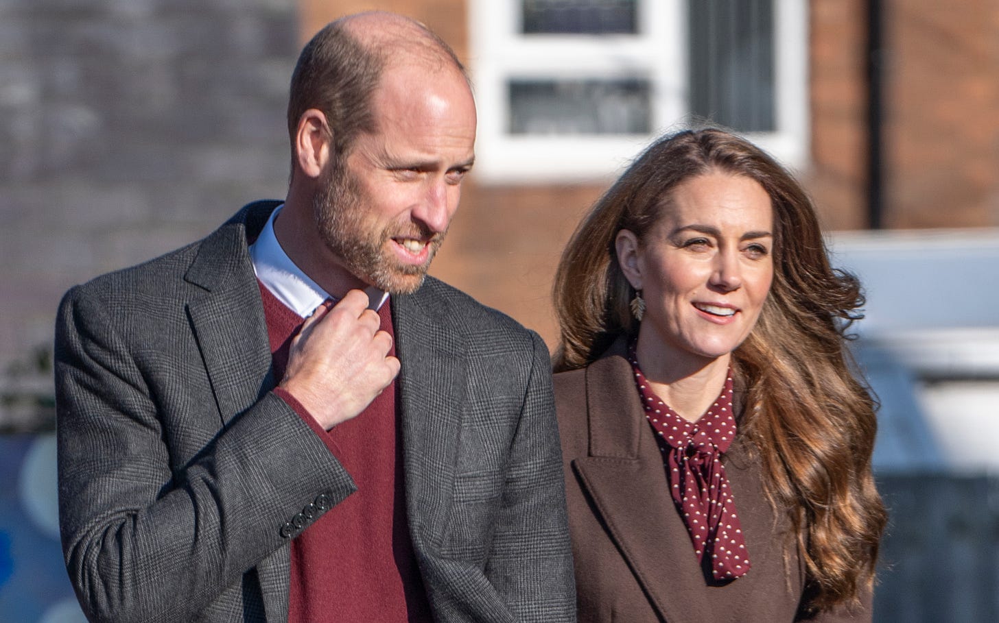 Prince William smiling in a suit walking next to Princess Catherine in a brown suit smiling Prince William smiling in a suit walking next to Princess Catherine in a brown suit smiling