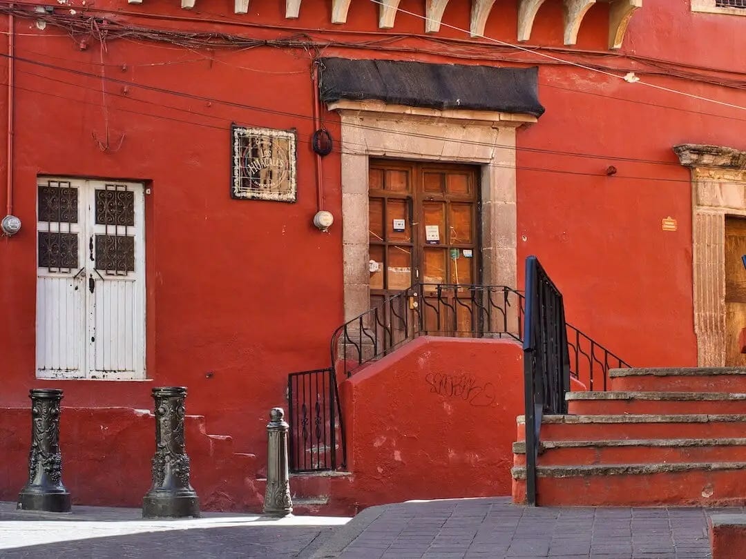A red building with a studded wooden door