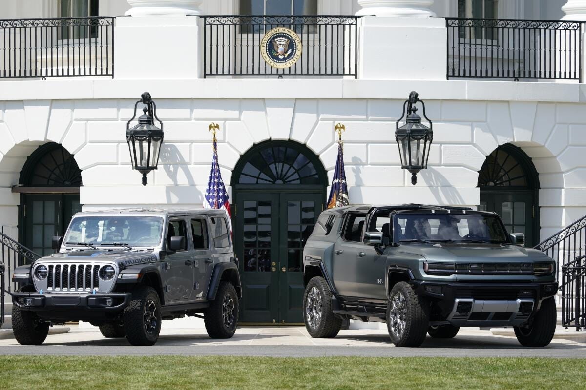 Two cars are shown on a driveway with flags behind them. Two cars are shown on a driveway with flags behind them.