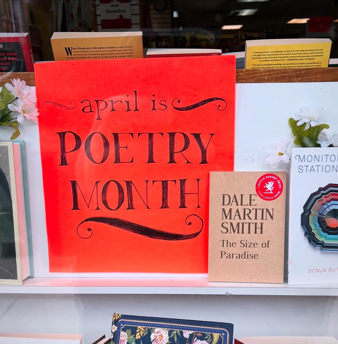 Shop window with red sign promoting April as Poetry MOnth and a copy of The Size of Paradise on display.
