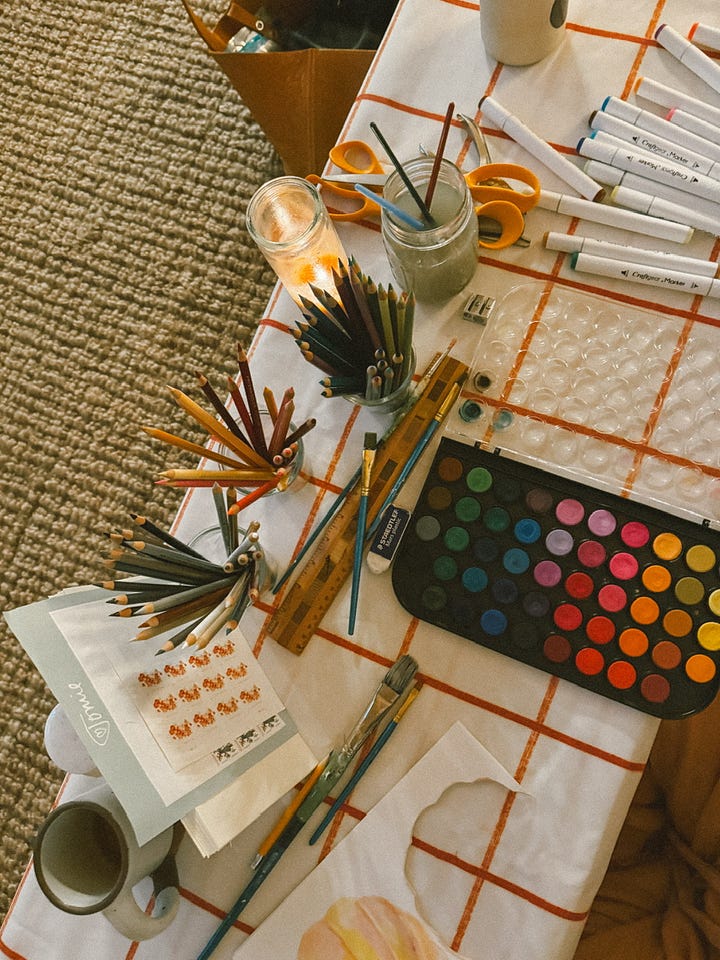 An aerial view of a white and red checkered table covered in art supplies.