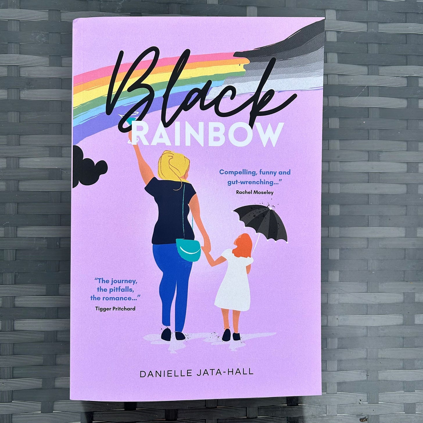 purple book cover with title blac rainbow, image of rainbow and mum holding girls hand