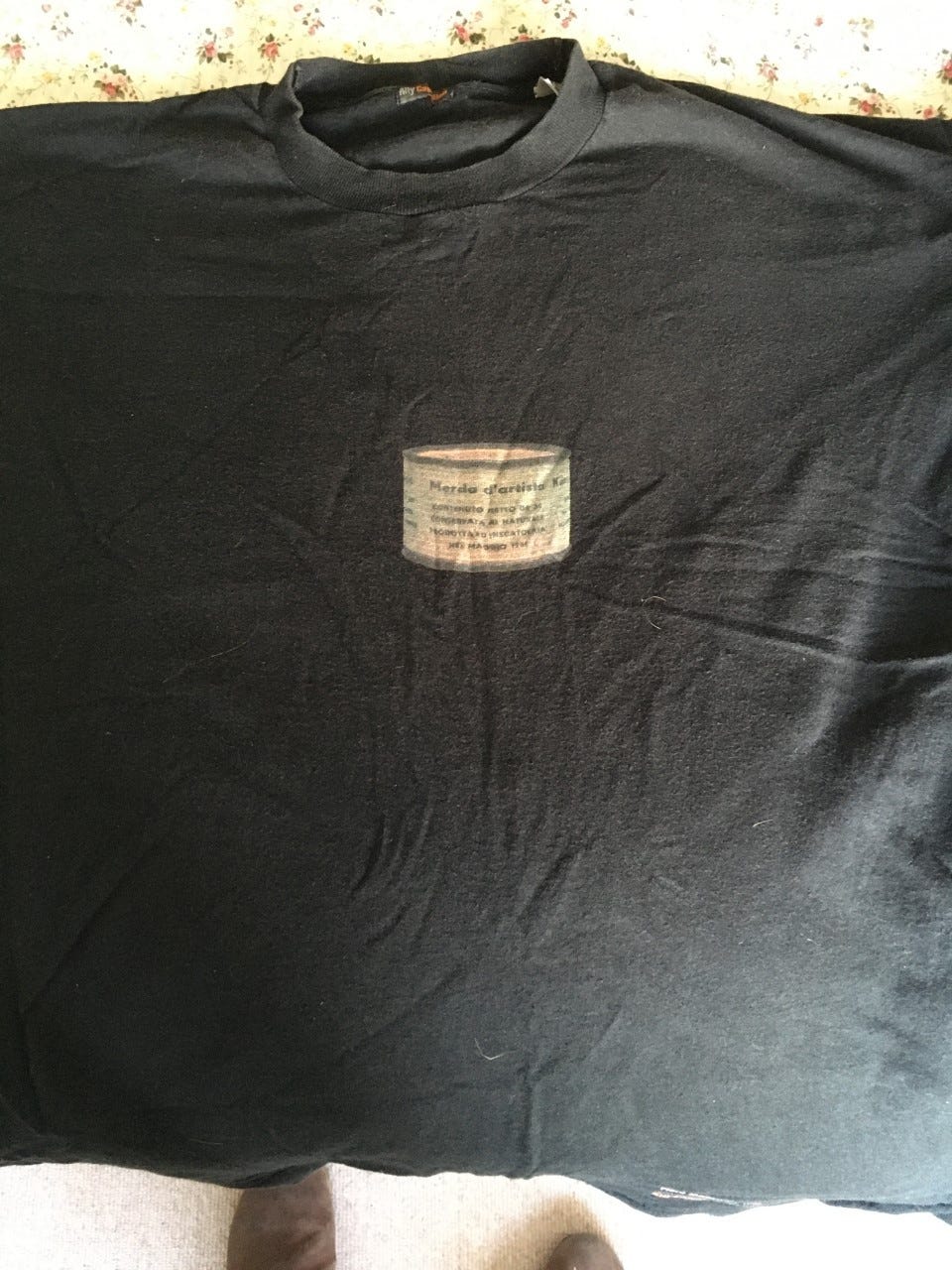 A black T-shirt with a photo of one of Manzoni’s Merda d’Artista tins on it
