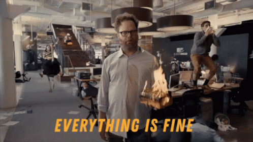 a man in an office holding a burning piece of wood with the words everything is fine behind him