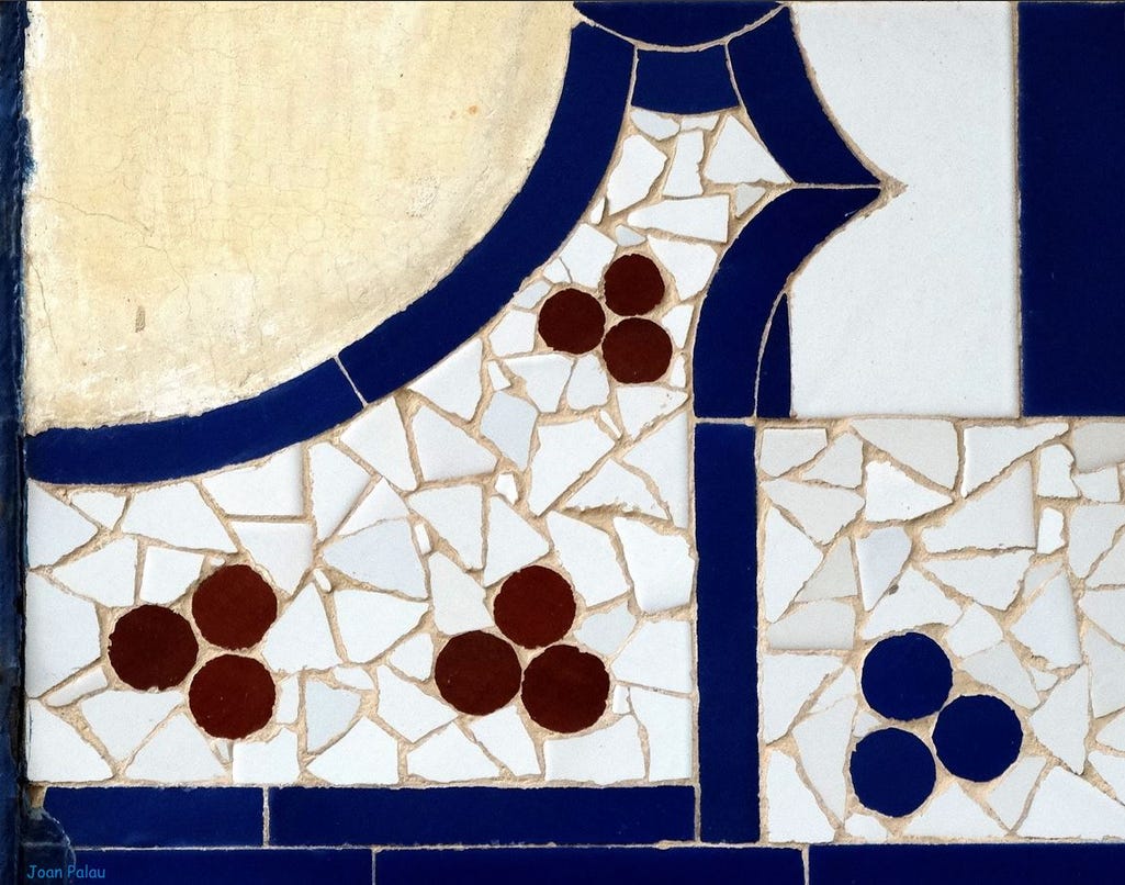 Un disegno geometrico di linee e curve costruito con pezzetti di ceramica colorata di bianco, blu e marroncino: è il dettaglio della facciata di un edificio modernista.