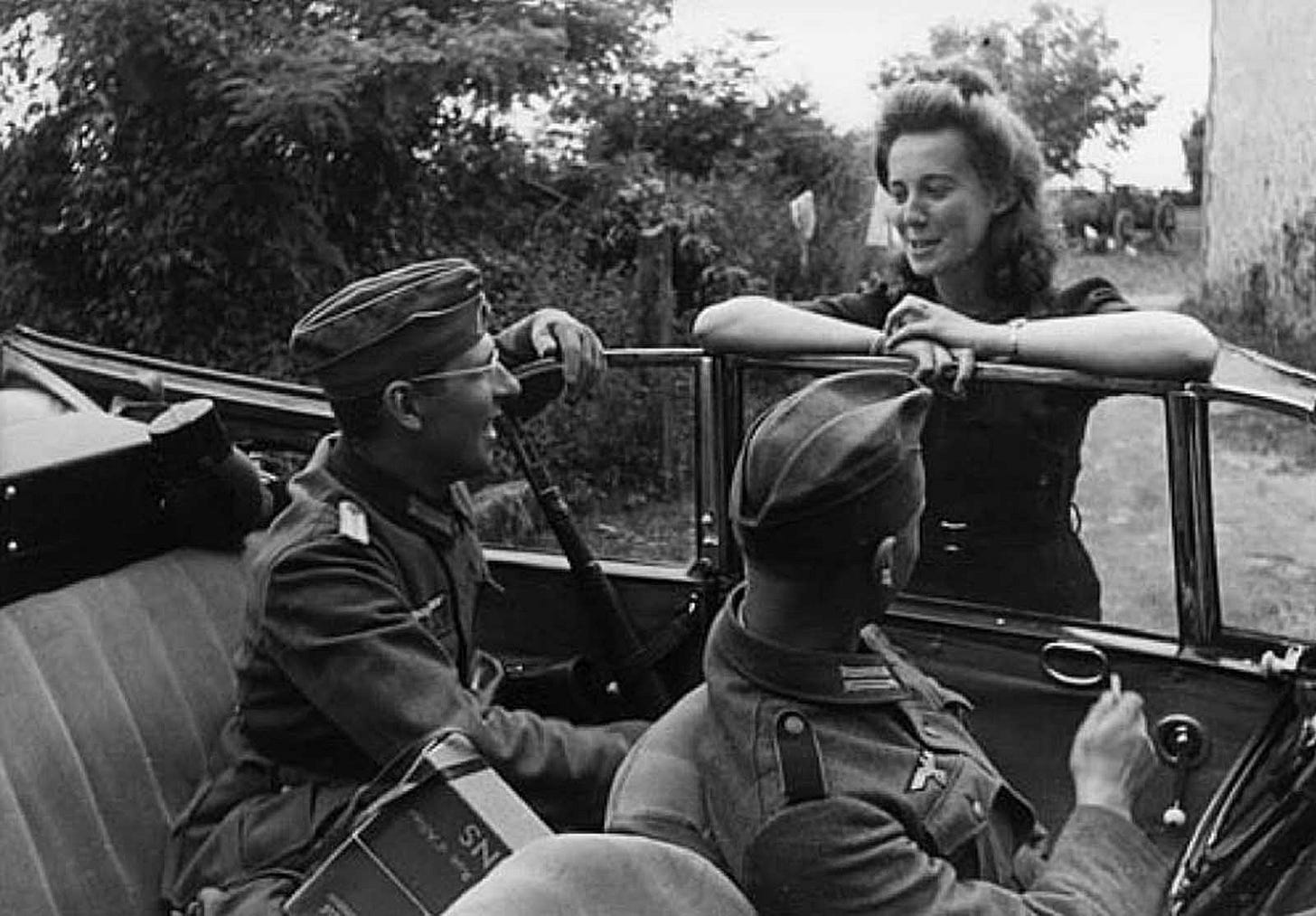 German soldiers engaging in conversation with a French woman, illustrating everyday interactions during the occupation. German soldiers engaging in conversation with a French woman, illustrating everyday interactions during the occupation.