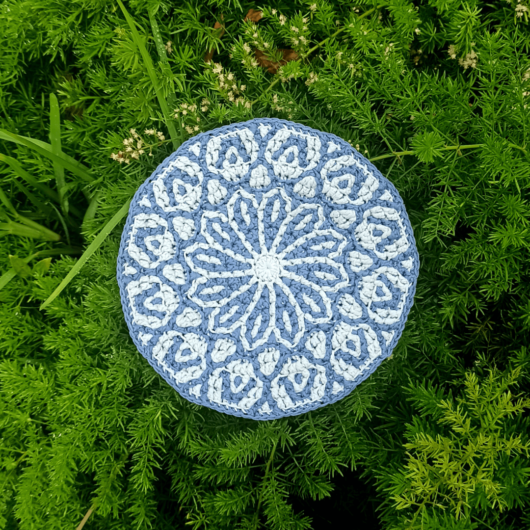 Round mosaic crochet project in two tones of blue cotton, with flower mandala design.
