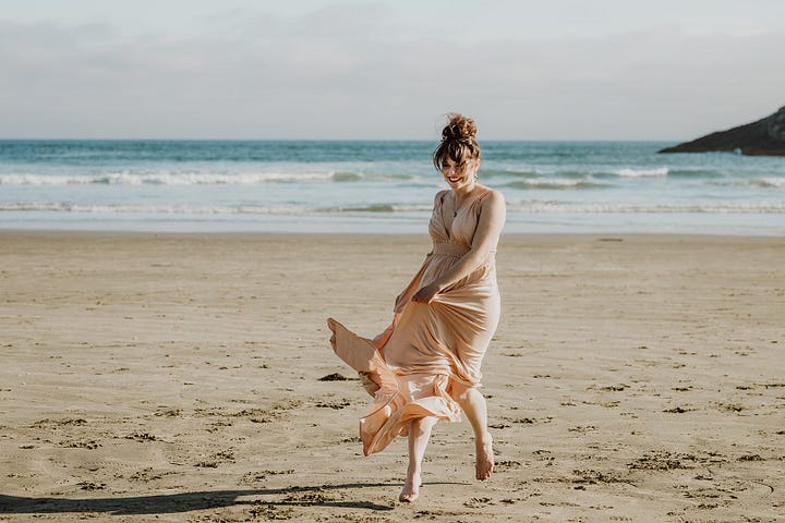 Beach front Tofino arranged photo shoot A couple posing on the rock, Videographer Brittany Ballamy running in the sand, surfer Emily Ballard sitting on the beach and a women in Reclamation company dress posing on rocks over looking the water