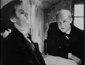 A short-range shot from the 1970 film Crime and Punishment. A scene from the conversation between Raskolnikov, played by Grigori Taratorkin on the left, and Porfiry Petrovich, played by Inokenti Smaktunovsky in the right. The conversation takes place in the small ‘coffin-size’ attic room rented by Raskolnikov A short-range shot from the 1970 film Crime and Punishment. A scene from the conversation between Raskolnikov, played by Grigori Taratorkin on the left, and Porfiry Petrovich, played by Inokenti Smaktunovsky in the right. The conversation takes place in the small ‘coffin-size’ attic room rented by Raskolnikov