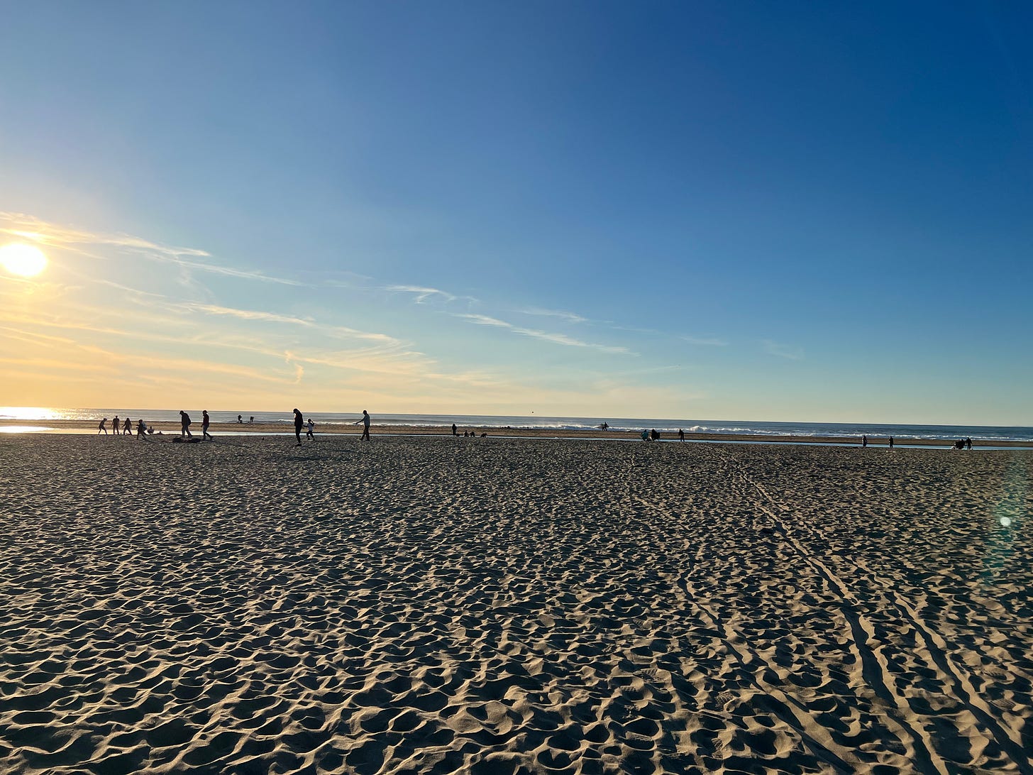a photo of Ocean Beach with the sun going down and people walking