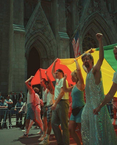 Three historical images showing Gilbert Baker’s mile-long rainbow flag from 1994. The first is an aerial view of the flag running down a packed New York City street. The second shows Gilbert Baker sitting on the flag in a park, surrounded by people holding it up. The third is a street-level view of LGBTQIA+ activists marching with a section of the flag in front of St. Patrick’s Cathedral, raising fists and celebrating queer liberation.