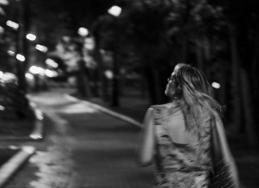 a woman walking down a street at night