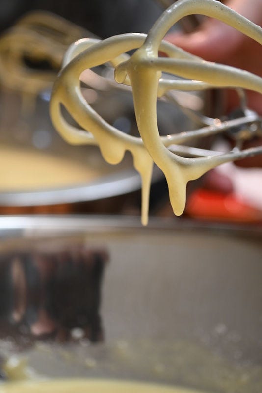 Close-up of a beater with yellow batter dripping, set against a blurred kitchen background, conveying a sense of baking in progress. Close-up of a beater with yellow batter dripping, set against a blurred kitchen background, conveying a sense of baking in progress.