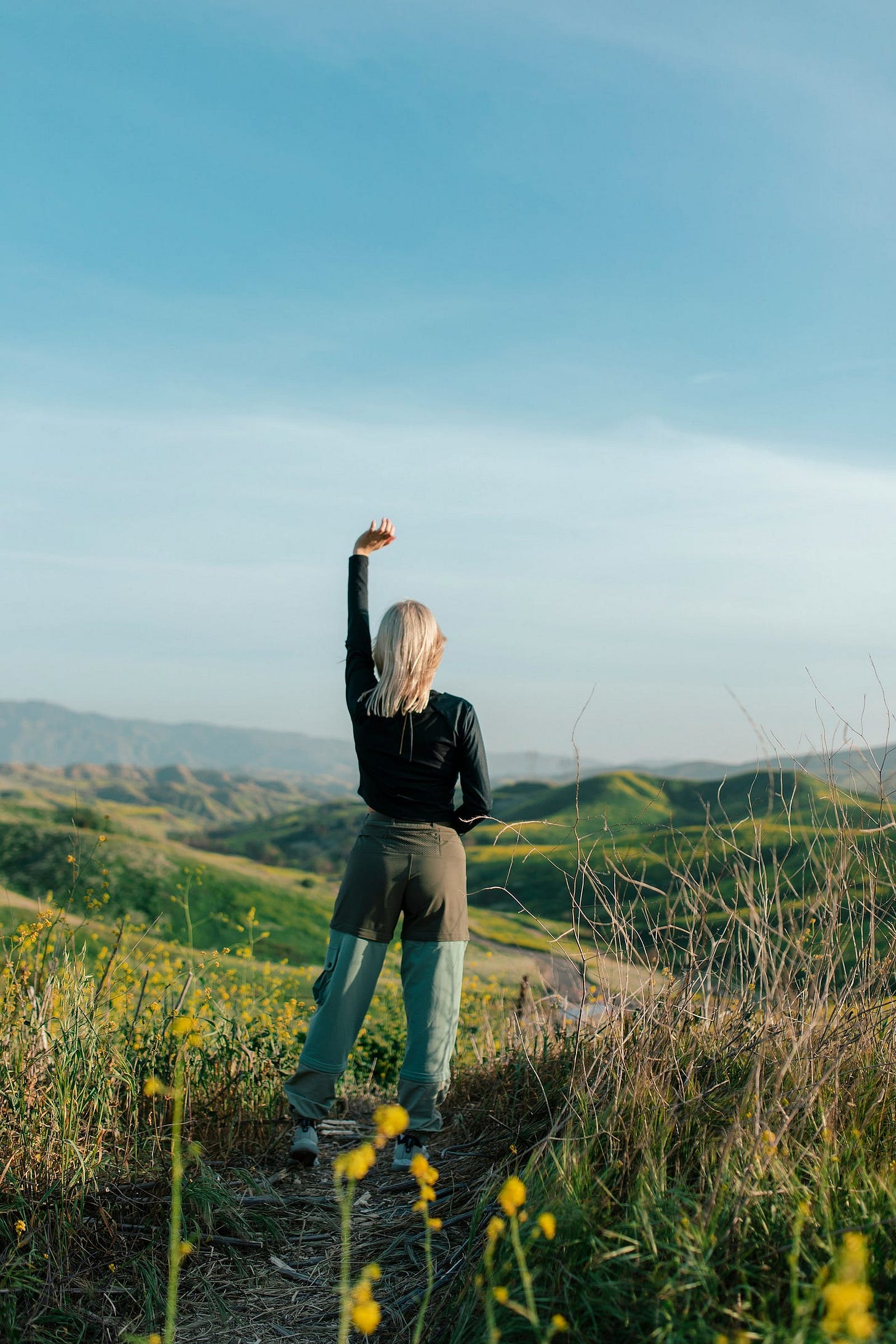 A woman standing alone in a picture-perfect green scenic mountain A woman standing alone in a picture-perfect green scenic mountain