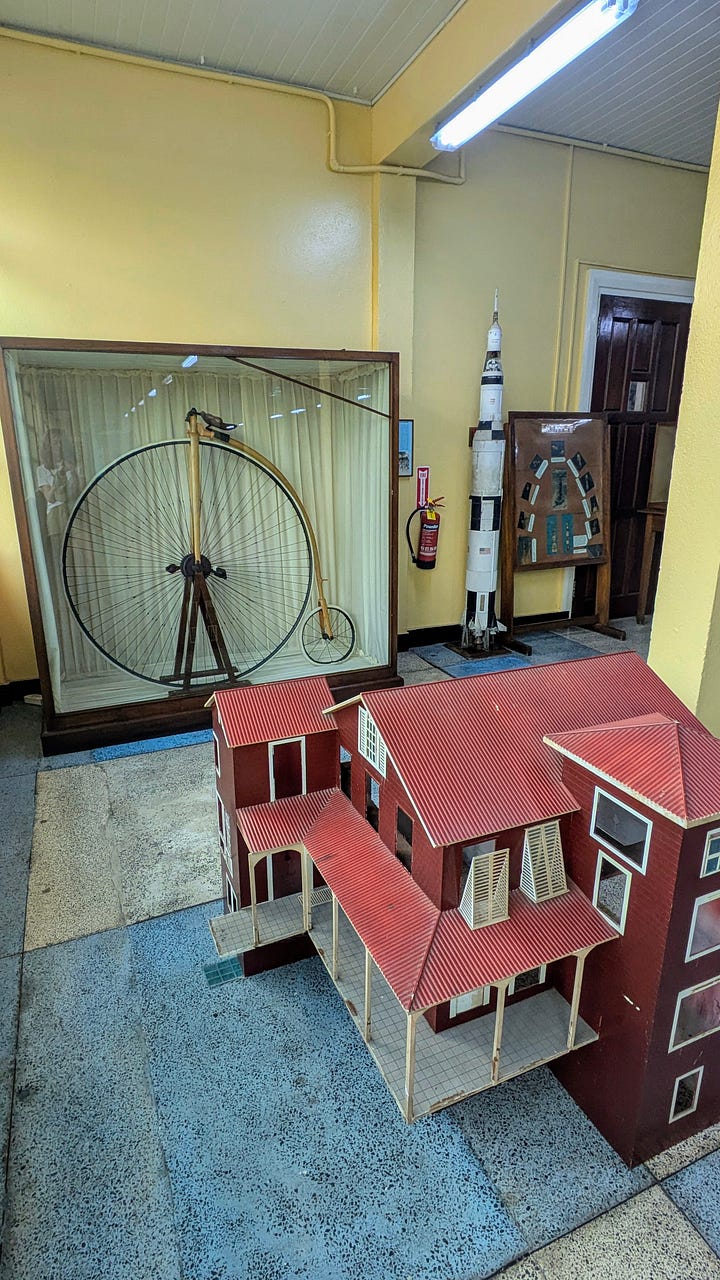 (It's a photo of a penny farthing and a dolls house, plus a giant sloth)