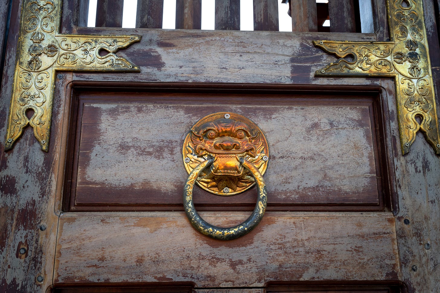 creepy golden knocker on an old wooden door