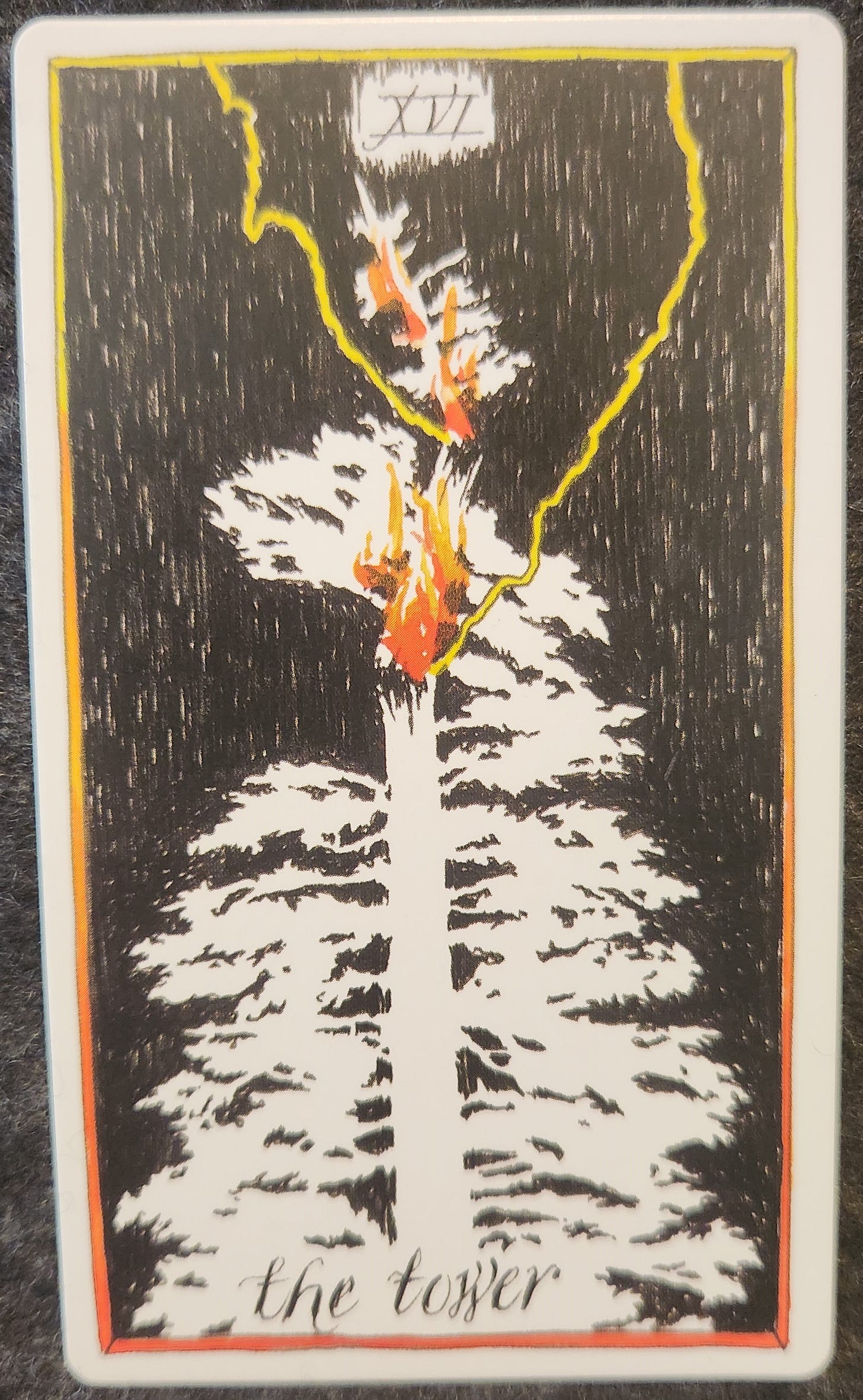 A tarot card labelled XVI the tower. A white pine tree has been struck by lightning. The top of the tree has been severed from the tree and the trunk is on fire. 