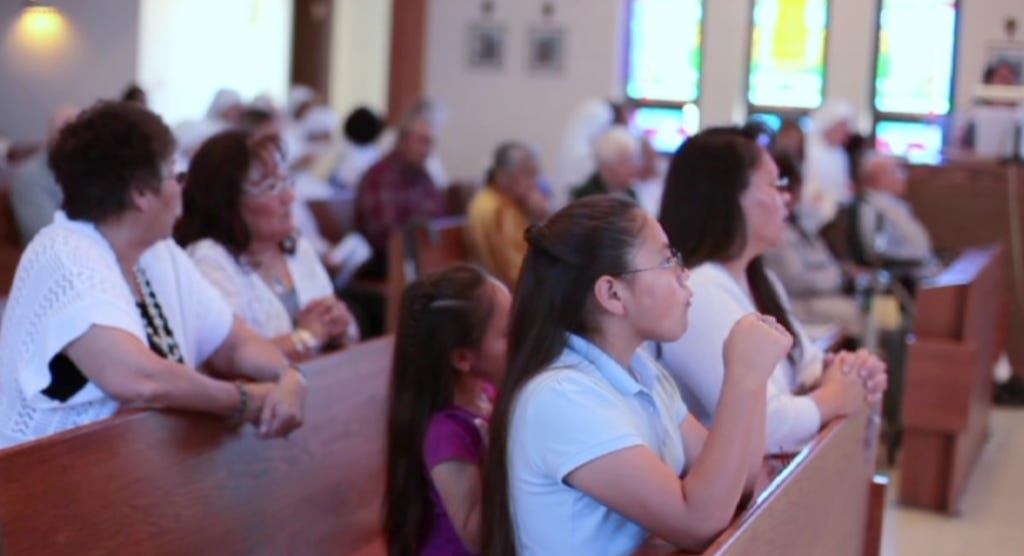 Still from the Navajo Mass DVD - families watch during the liturgy.