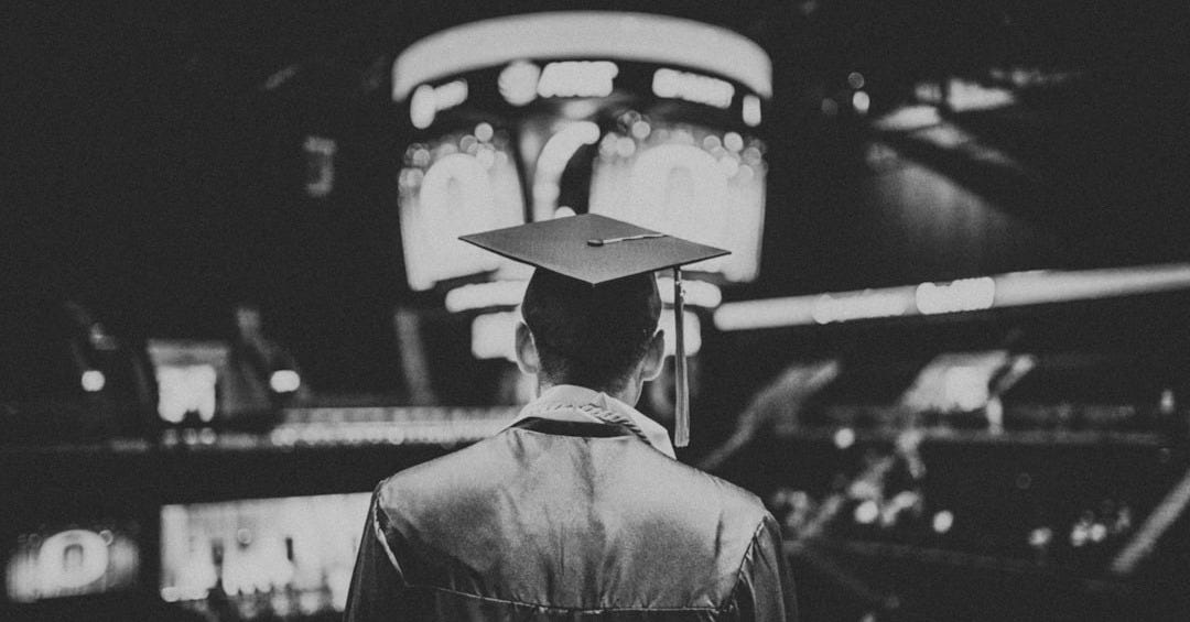man in academic dress wearing mortar cap
