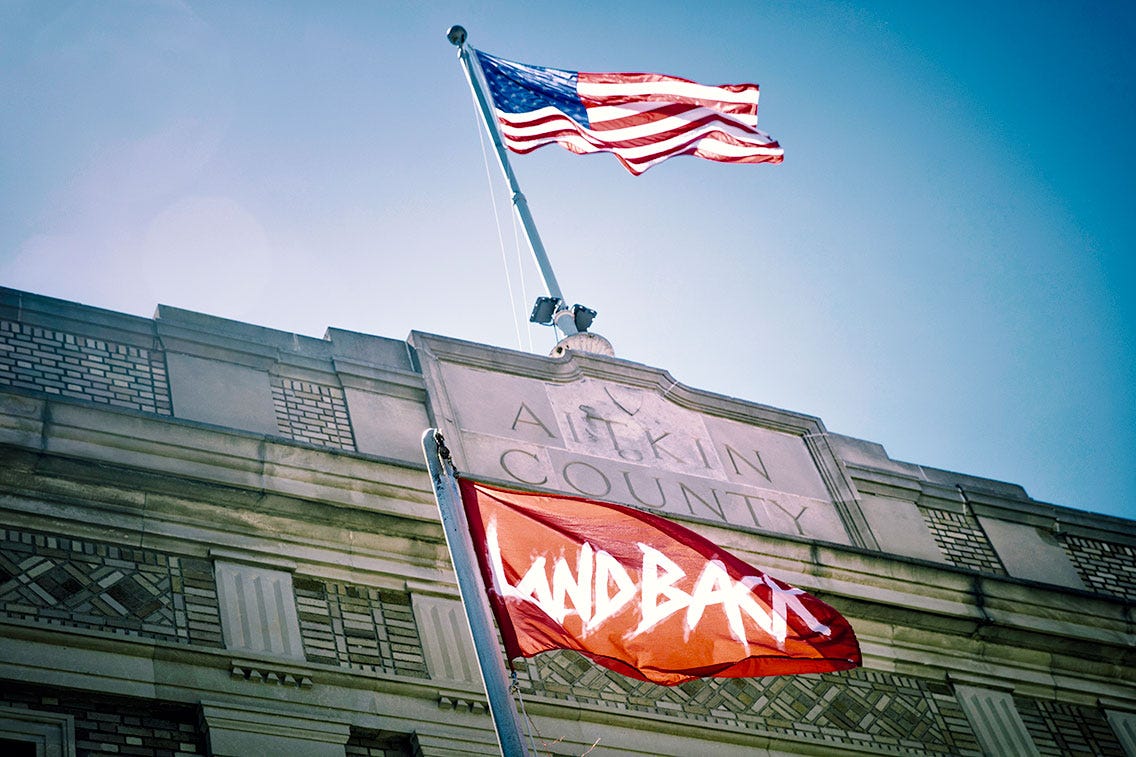 A Land Back flag flies under the US Flag outside Aitkin County Courthouse in Aitkin, Minnesota