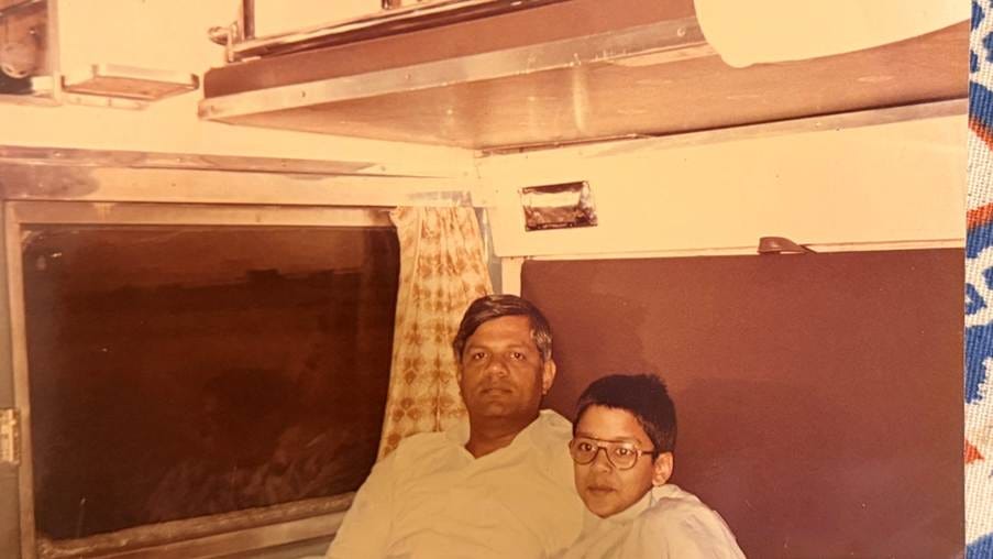 A warm-toned vintage photograph of my father and me as a young boy, sitting together in an Indian Railways sleeper coach. A warm-toned vintage photograph of my father and me as a young boy, sitting together in an Indian Railways sleeper coach.