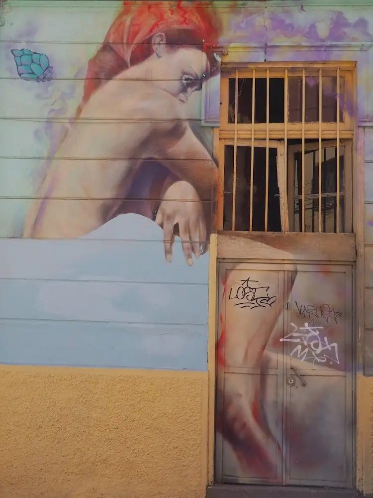 Street art - a sideways view of a woman with red hair sitting up on a bed