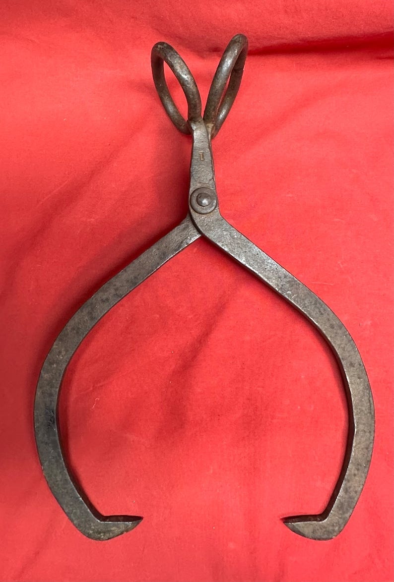 May include: Antique iron tongs with a double loop handle. The tongs are rusty and have a worn finish.