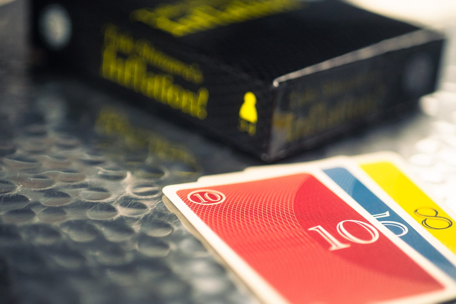 Cards from the game Inflation! with the game box behind them.