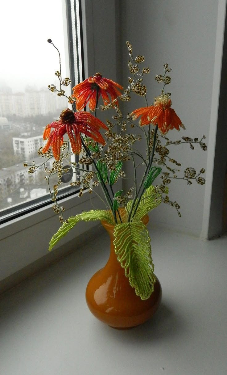 This may contain: an orange vase filled with flowers on top of a window sill