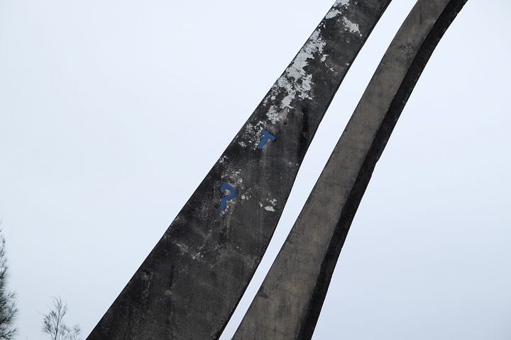closeup view concrete arches with faint blue letters set against grey sky