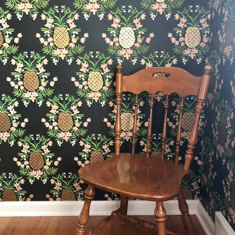 Hipster wallpaper with gilt pineapples, green leaves, and pale pink flowers.