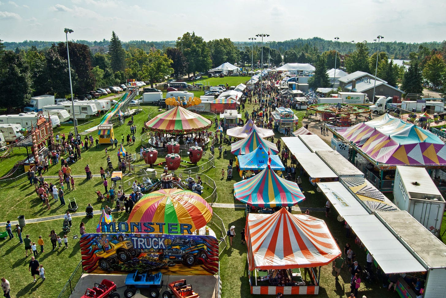 An aerial view of rides, tents, games, trailers, and people at the fair.