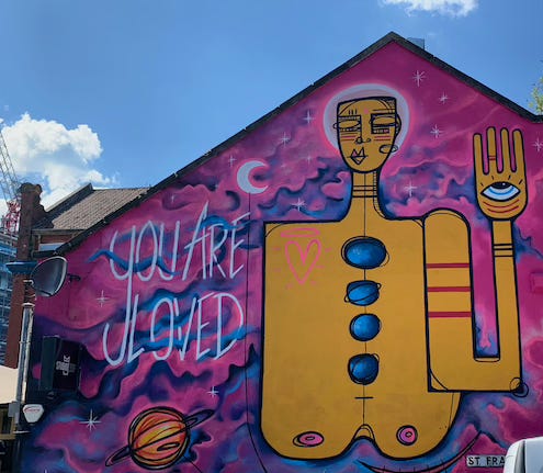 Image shows a piece of urban art painted on the end wall of a house (in Bristol, UK). In the art, the phrase, "You are Loved" is written.
