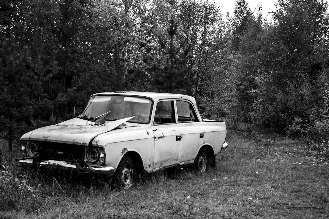 an old blue car is parked in a field