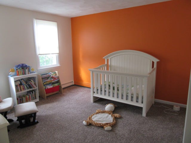 Nursey with orange accent wall. Nursey with orange accent wall.