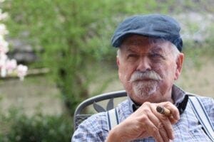 Middle aged man in a blue cap smoking a cigar