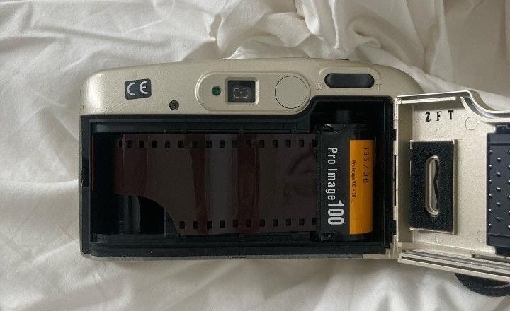 This may contain: an old camera is laying on a bed with its flash drive in it's case