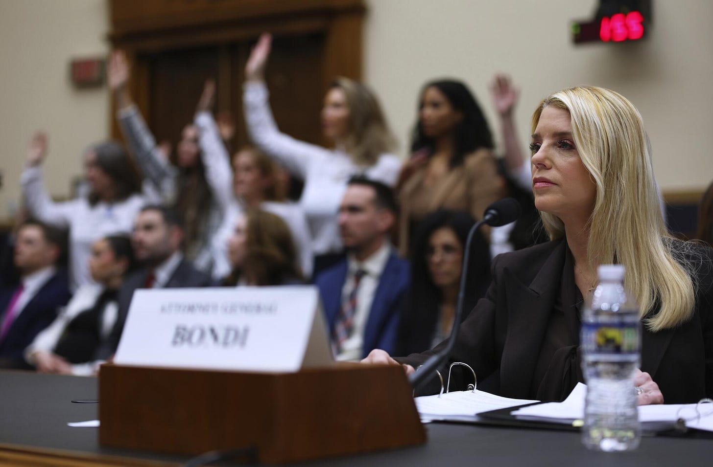 Attorney General Pam Bondi testifies before a House Judiciary Committee as Jeffrey Epstein survivors behind her. 