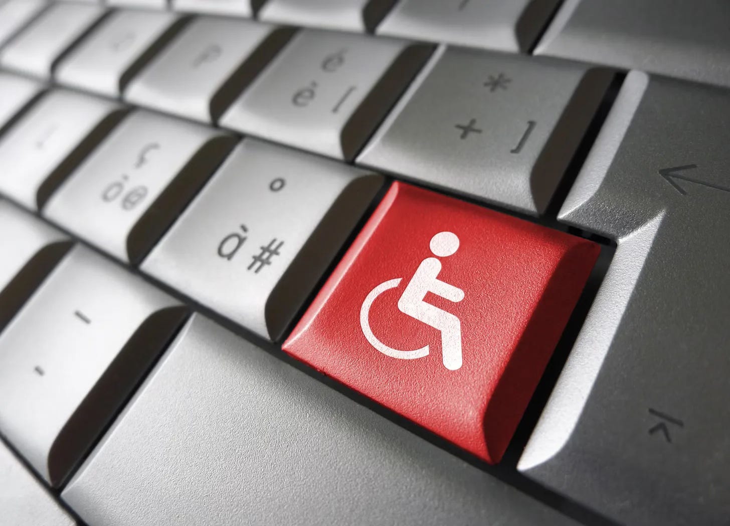 Closeup of a computer keyboard with one red key with a white wheelchair symbol