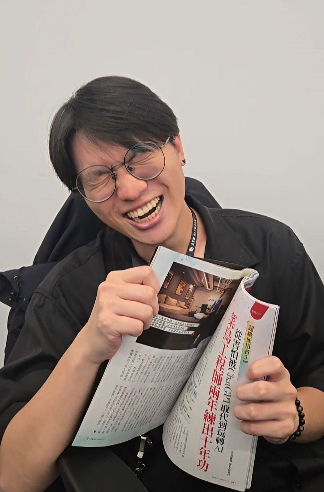 可能是 1 人、讀書、微笑、眼鏡和文字的圖像