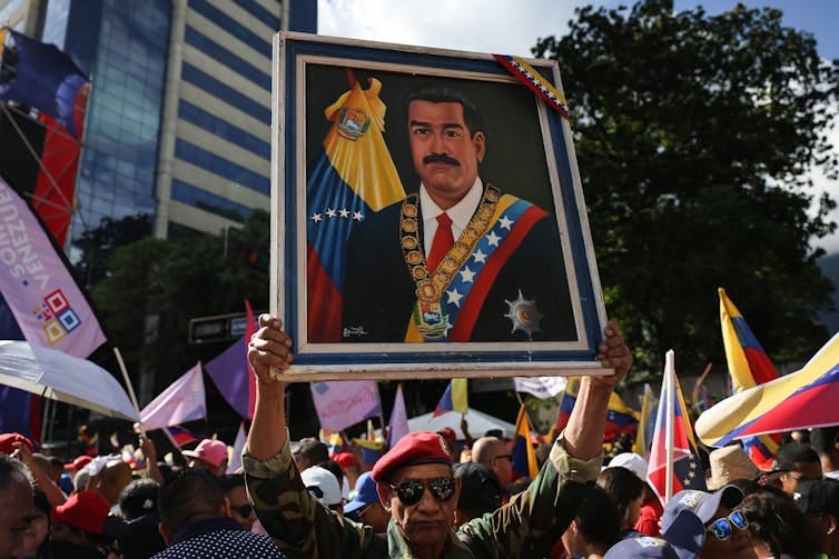 A large painting of a man is held aloft. A large painting of a man is held aloft.