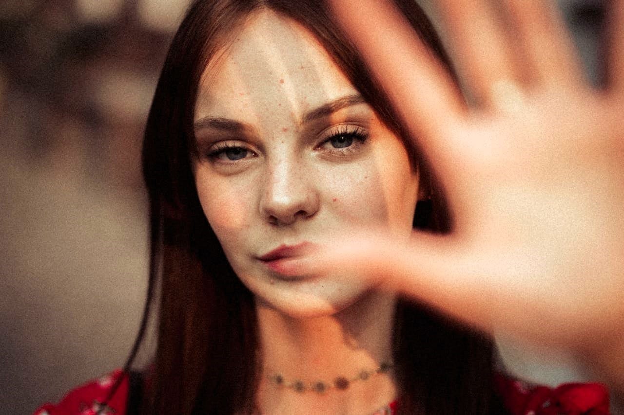 An attractive dark haired woman holding her hand up to the camera