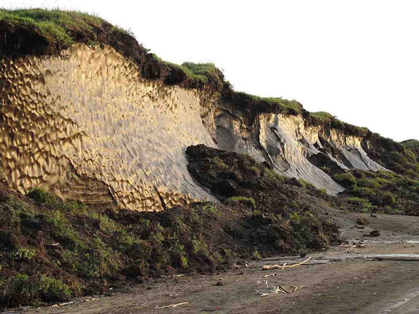 Photo of eroded land, tens of feet tall exposing former permafrost. Photo of eroded land, tens of feet tall exposing former permafrost.